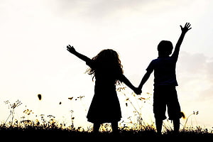 Silhouette of Two Children Holding Hands in a Field at Sunset HD wallpaper