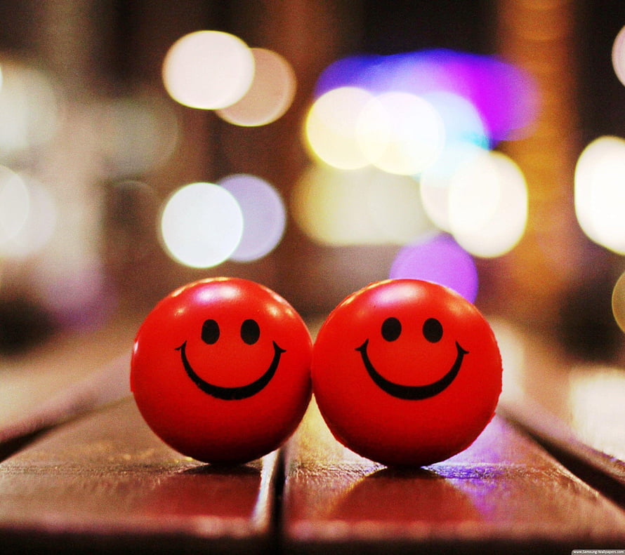 Two Red Smiley Face Balls on Wooden Surface with Bokeh Lights HD wallpaper