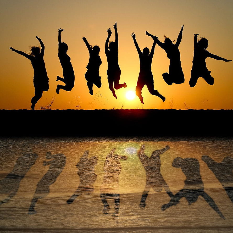 Silhouetted friends jumping joyfully at sunset with reflections on wet sand HD phone wallpaper