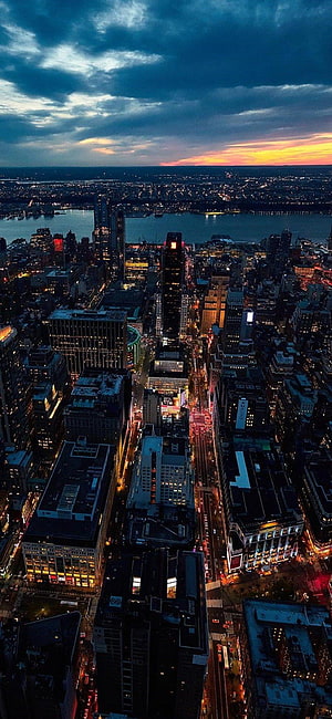 Aerial View of New York City Skyline at Dusk with Dramatic Clouds and Illuminated Streets HD phone wallpaper