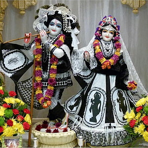 Radha Krishna Murti in Black and White Mourning Attire with Floral Garlands HD phone wallpaper