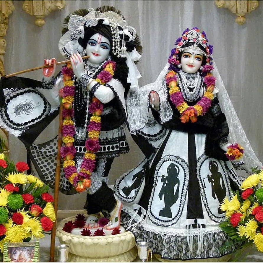 Radha Krishna Murti in Black and White Mourning Attire with Floral Garlands HD phone wallpaper