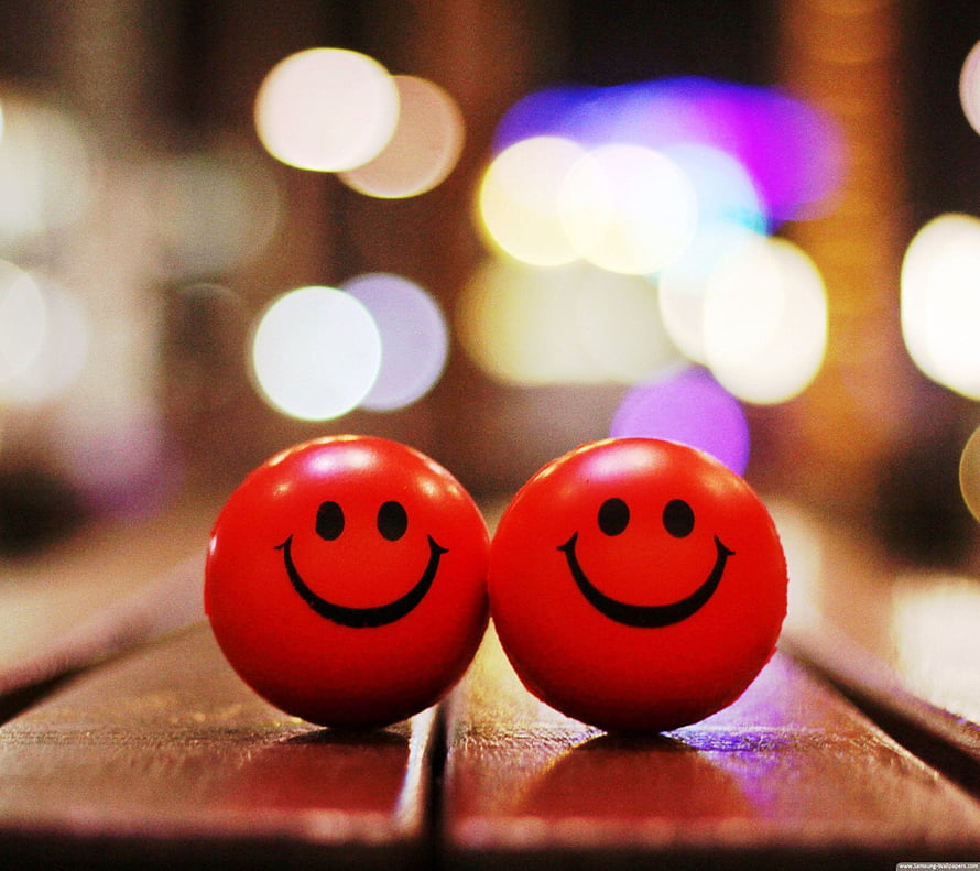 Two Red Smiley Face Orbs on Wooden Surface with Bokeh Lights HD wallpaper