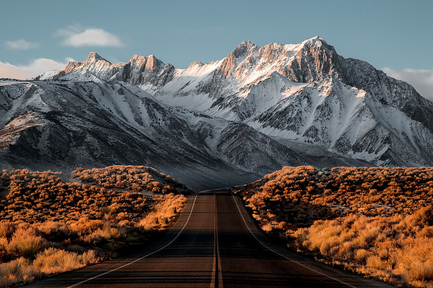 Snow-Capped Mountain Range Along a Desert Highway at Golden Hour HD wallpaper