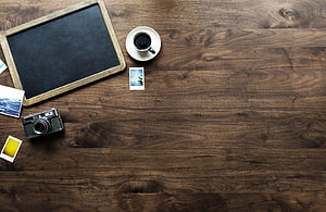 Rustic wooden desk flat lay with vintage camera, coffee cup, and instant photos HD wallpaper