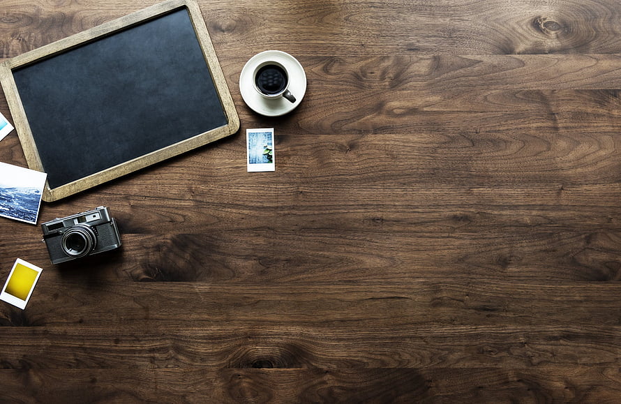 Rustic wooden desk flat lay with vintage camera, coffee cup, and instant photos HD wallpaper