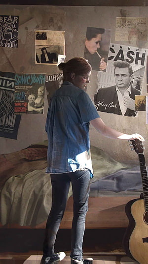 Ellie from The Last of Us Part 2 standing in a room with a guitar and music posters HD phone wallpaper