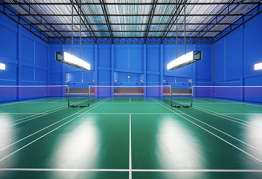 Empty Indoor Badminton Court with Green Floor and Blue Walls Under Bright Overhead Lighting HD wallpaper