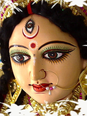 Close-up of Maa Durga idol face with third eye, crescent moon, and ornate gold jewelry HD phone wallpaper