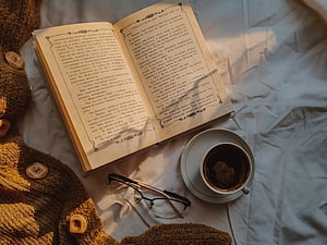 Cozy Reading Scene With Open Book, Coffee, Glasses, And Knit Sweater On White Linen HD wallpaper