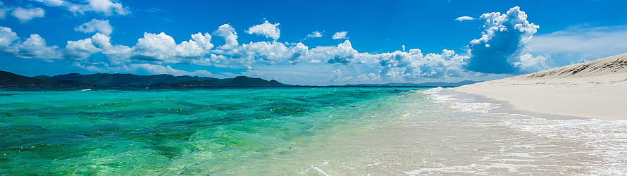 Turquoise Lagoon Meets White Sand Beach Under a Bright Blue Sky HD wallpaper