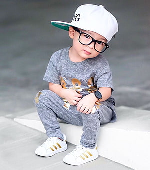 Stylish Toddler Boy in Grey Streetwear Outfit with White Cap and Glasses HD phone wallpaper