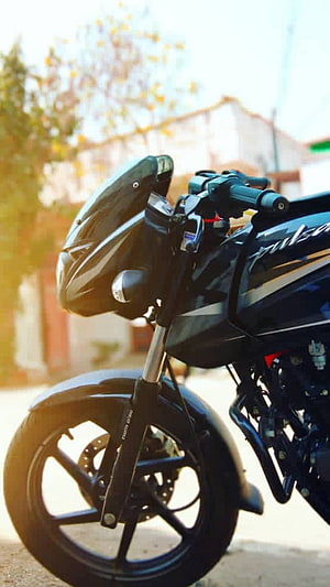 Close-up of a black Bajaj Pulsar 150 motorcycle front end with headlight and wheel HD phone wallpaper