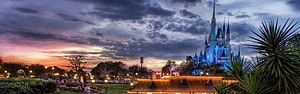 Cinderella Castle at Walt Disney World during a dramatic sunset with warm park lighting HD wallpaper