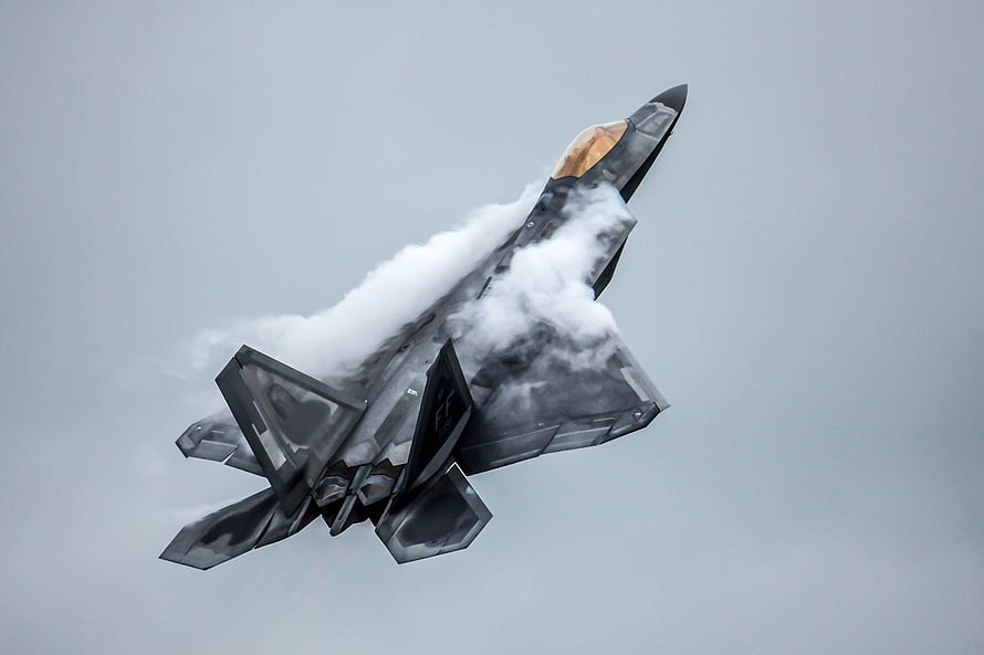 F-22 Raptor Stealth Fighter Jet Banking Through Clouds in Overcast Sky HD wallpaper
