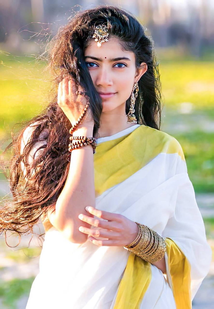 Sai Pallavi in a white and yellow saree with traditional gold jewelry and long flowing hair HD phone wallpaper