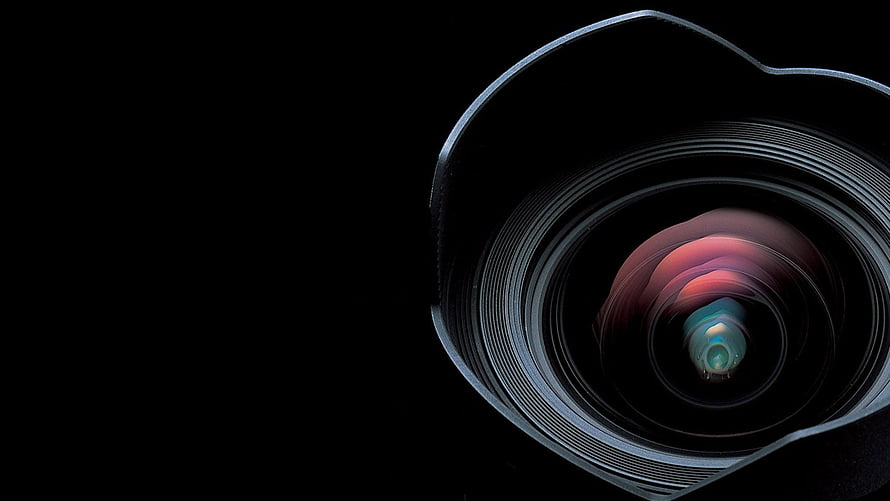 Close-up of a camera lens with colorful reflections on a black background HD wallpaper