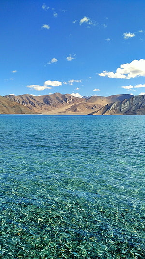 Pangong Lake in Ladakh with crystal clear turquoise water and arid mountain ranges under a bright blue sky HD phone wallpaper