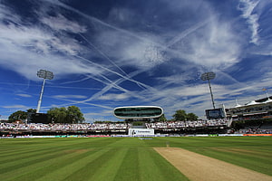 Lords Cricket Ground with striped outfield, packed stands, and a dramatic blue sky with contrails HD wallpaper