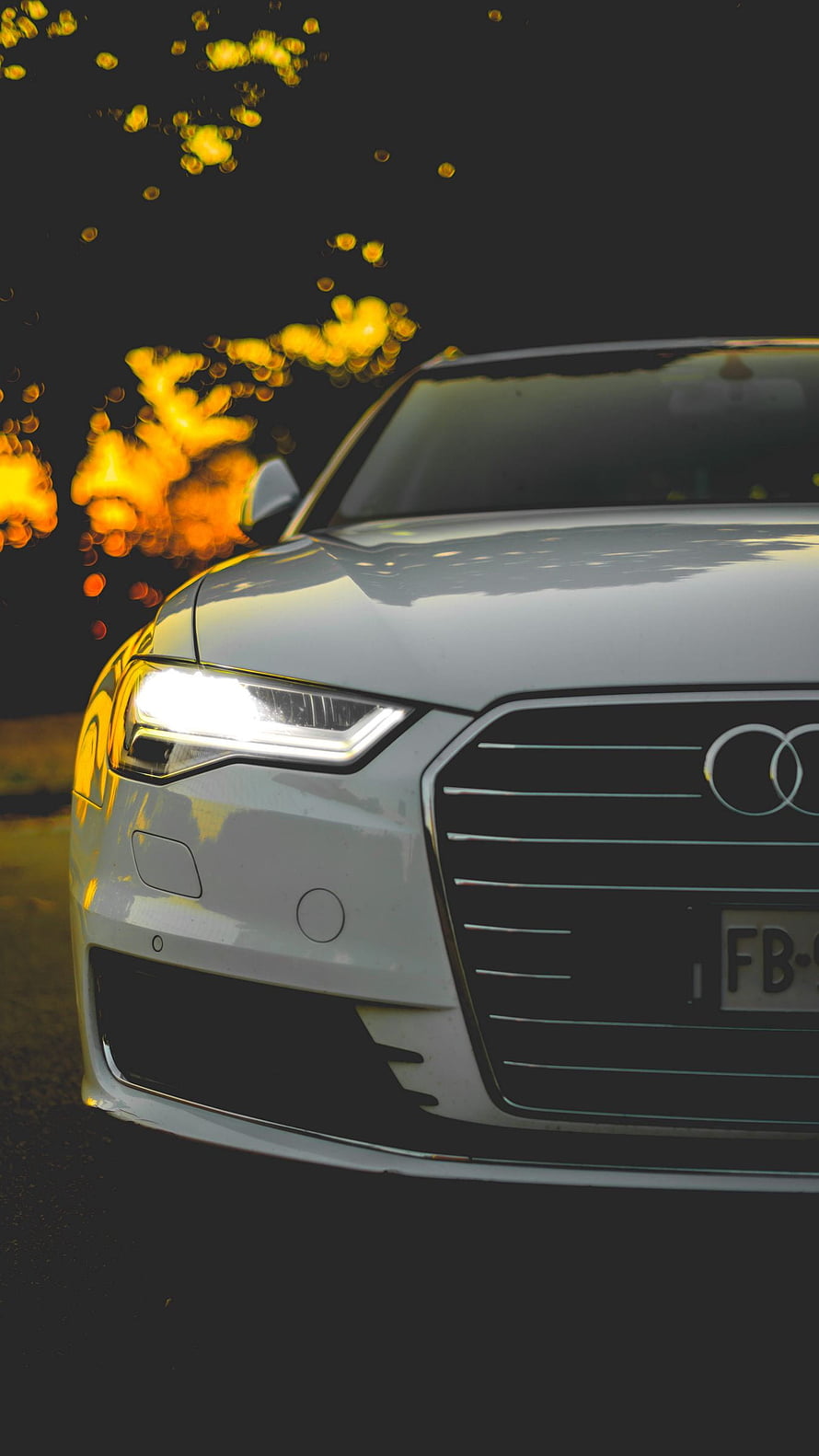 White Audi Front Grille Close-Up with Golden Bokeh and Dramatic Lighting HD phone wallpaper