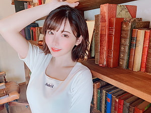 Eimi Fukada in a white Soleil t-shirt posing in front of a wooden bookshelf filled with vintage books HD wallpaper