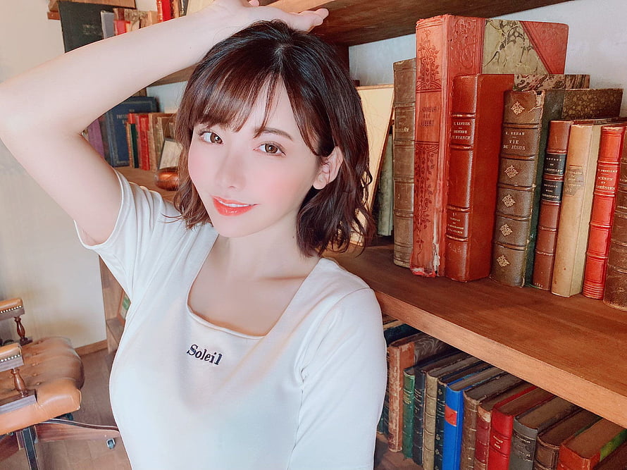 Eimi Fukada in a white Soleil t-shirt posing in front of a wooden bookshelf filled with vintage books HD wallpaper