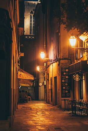 Narrow European Alleyway at Night with Warm Street Lamps and Historic Architecture HD phone wallpaper