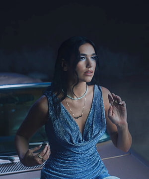 Dua Lipa in a shimmering blue gown with layered jewelry and dramatic makeup HD phone wallpaper
