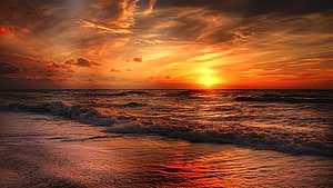 Vibrant Orange Sunset Over Ocean Waves on a Sandy Beach HD wallpaper