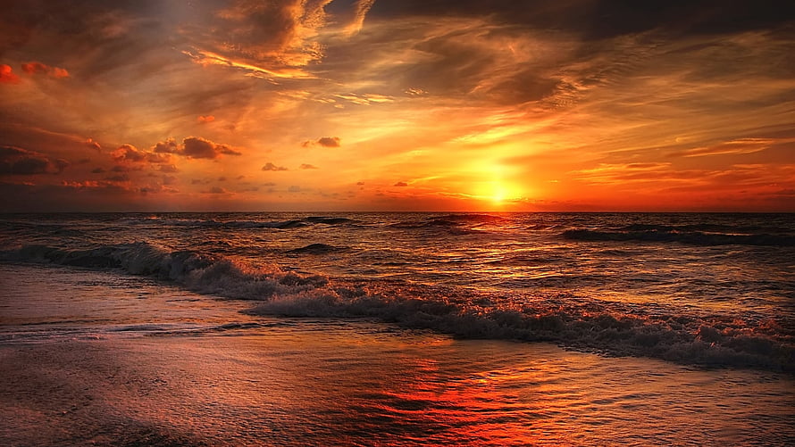 Vibrant Orange Sunset Over Ocean Waves on a Sandy Beach HD wallpaper