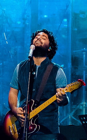 Arijit Singh performing live on stage with electric guitar under blue concert lighting HD phone wallpaper
