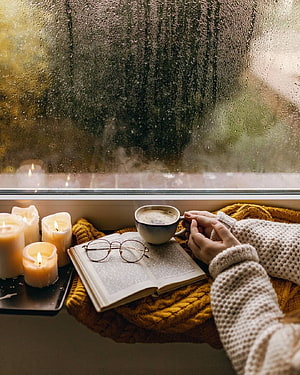 Cozy Autumn Reading Nook with Rainy Window, Candles, and Warm Coffee HD phone wallpaper