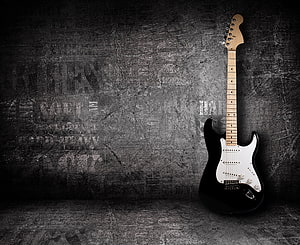 Black Electric Guitar Leaning Against Grunge Concrete Wall HD wallpaper