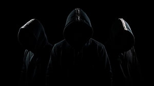 Three Silhouetted Figures in Black Hoodies Against a Dark Background HD wallpaper