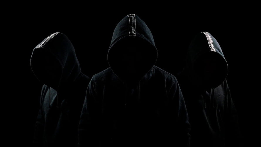 Three Silhouetted Figures in Black Hoodies Against a Dark Background HD wallpaper