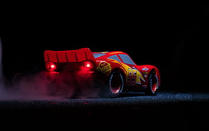 Lightning McQueen from Cars 3 drifting with smoke and glowing red taillights on a dark track HD wallpaper