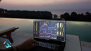 Laptop displaying stock market charts and trading data by an infinity pool at dusk HD wallpaper