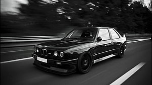 Black BMW E30 M3 Sedan Captured in Motion on a Forest Road HD wallpaper