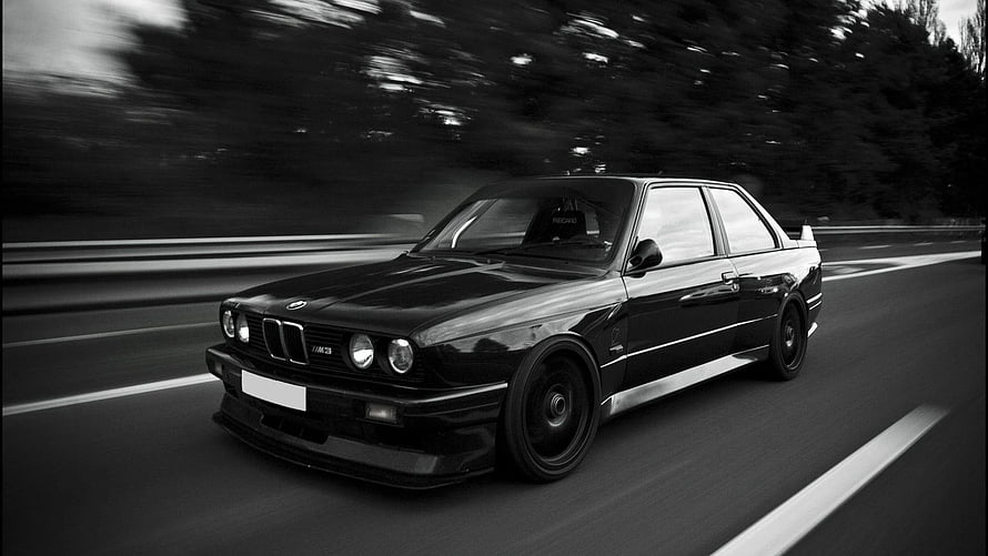 Black BMW E30 M3 Sedan Captured in Motion on a Forest Road HD wallpaper