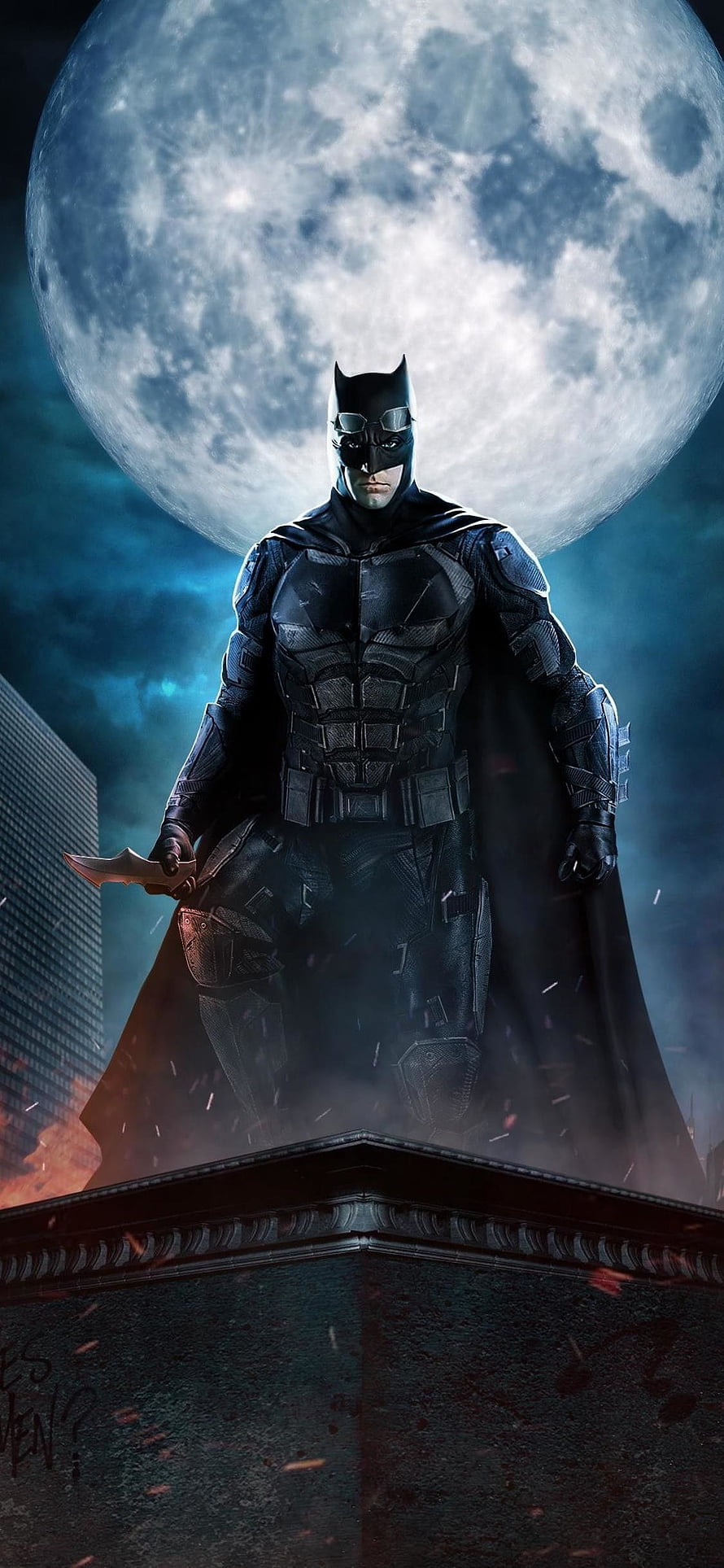 Batman in armored suit standing on rooftop under a full moon with batarang in hand HD phone wallpaper