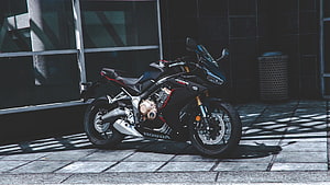 Black Honda CBR650R sport motorcycle parked on a city sidewalk with dramatic shadows HD wallpaper