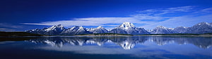Snow-Capped Mountain Range Reflected in a Calm Alpine Lake Under a Deep Blue Sky HD wallpaper