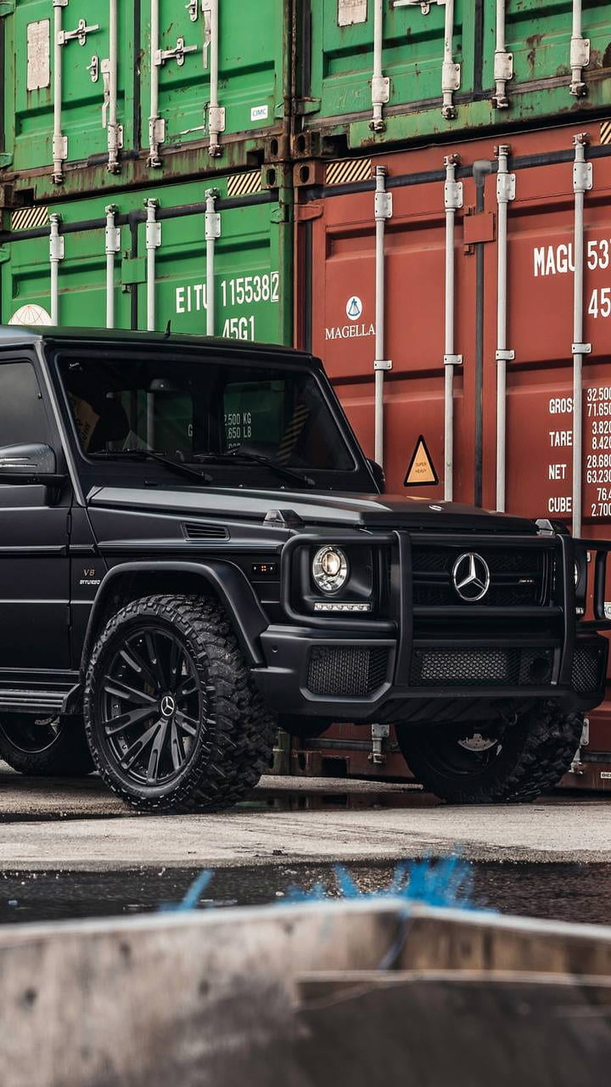 Black Mercedes-Benz G-Class SUV with Off-Road Tires Parked in Front of Stacked Shipping Containers HD phone wallpaper