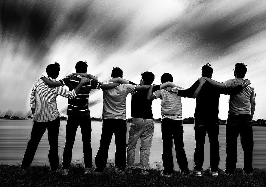 Seven friends standing arm in arm by a lake under a dramatic cloudy sky in black and white HD wallpaper