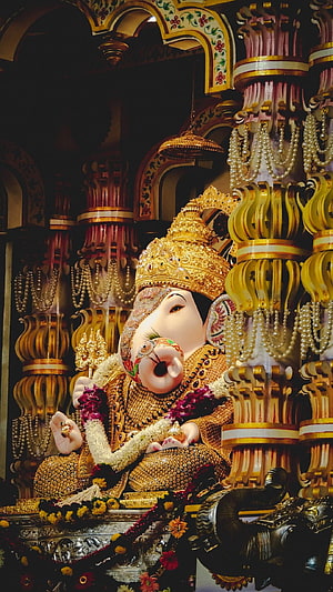 Ornate Ganesha Murti Adorned in Gold Jewelry and Floral Garlands Within Temple Sanctum HD phone wallpaper