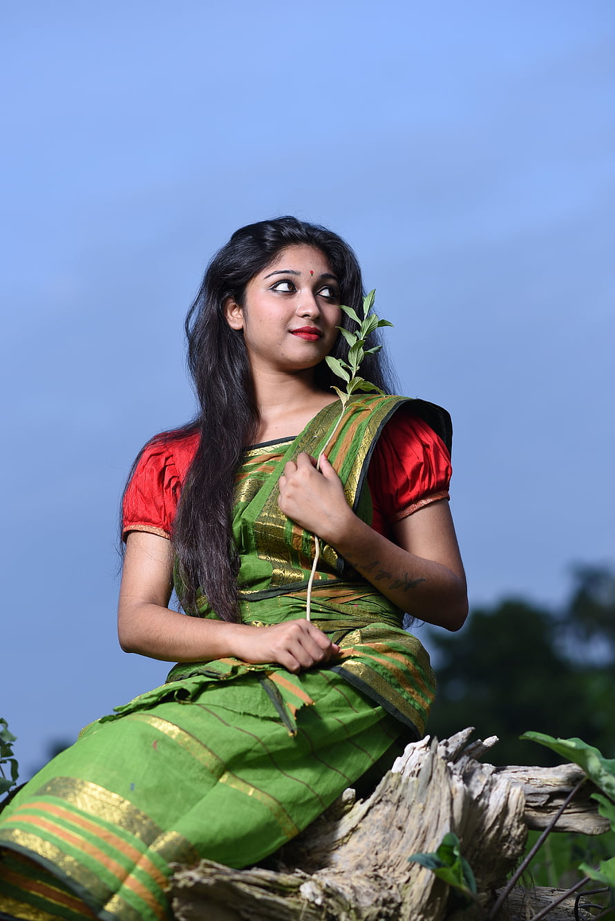 Bengali woman in green silk saree holding a leafy branch against a clear blue sky HD phone wallpaper