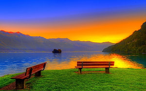 Serene Lake Sunset with Wooden Benches and Distant Mountains HD wallpaper