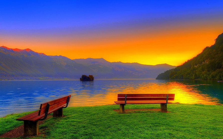 Serene Lake Sunset with Wooden Benches and Distant Mountains HD wallpaper