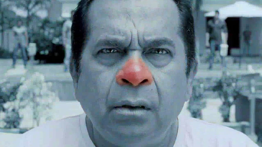 Brahmanandam in dramatic close-up with blue-tinted skin and red nose in outdoor scene HD wallpaper