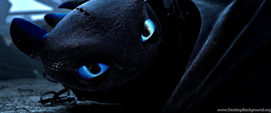 Close-up of Toothless the Night Fury with glowing blue eyes in a dark cinematic scene HD wallpaper